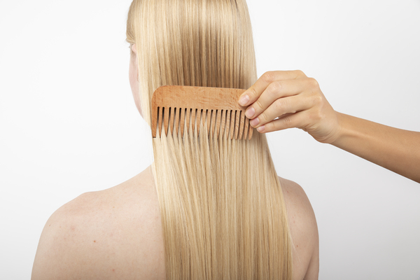 Woman combing hair with wide tooth comb